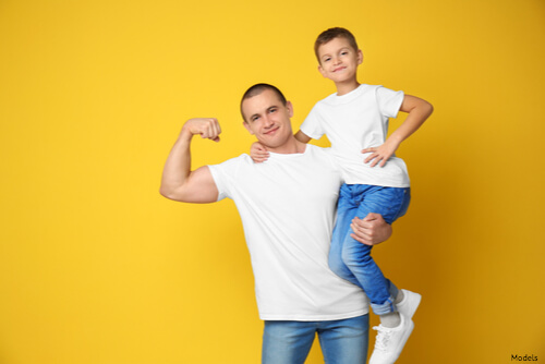 Dad flexing his bicep while holding his son