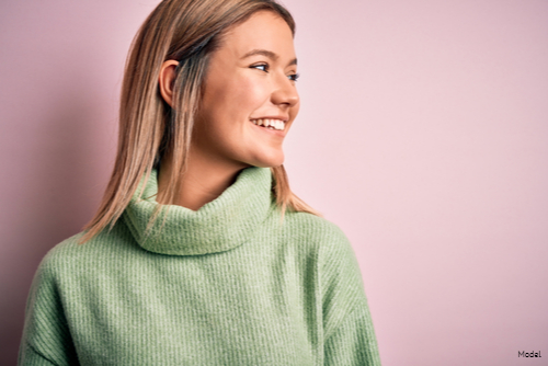 Smiling young woman with short straight blonde hair in a green sweater looking to the right