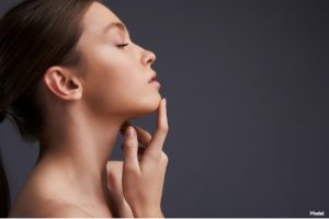 Serene woman with eyes closed gently touching her chin with her index finger