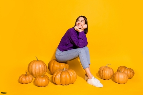 woman smiling, sitting on pumpkins