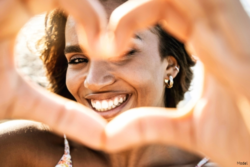 Smiling woman making a heart with her hands in front of her face